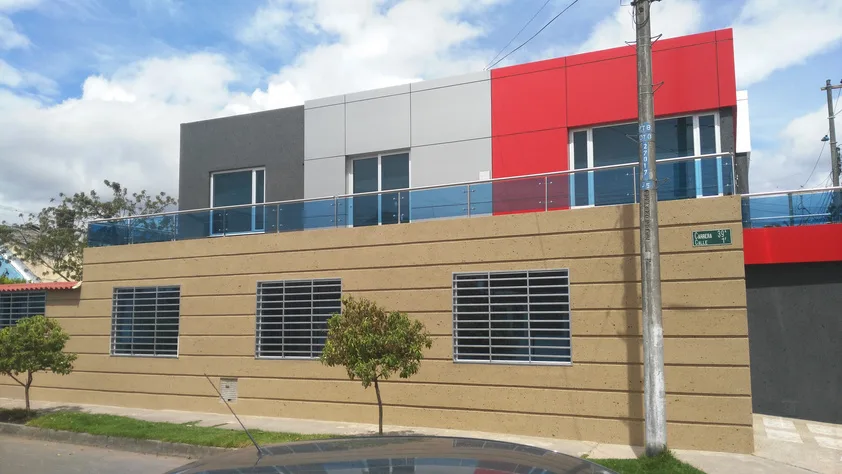 Casa contemporánea de dos niveles en Bogotá con volúmenes blanco, gris y rojo